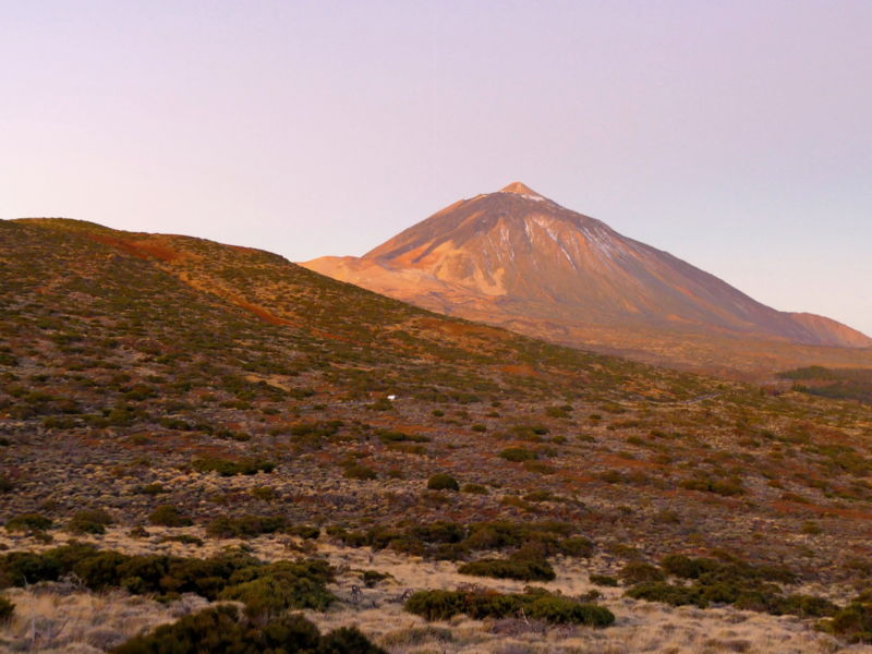 Der Teide leuchtet rot in der aufgehenden Morgensonne.