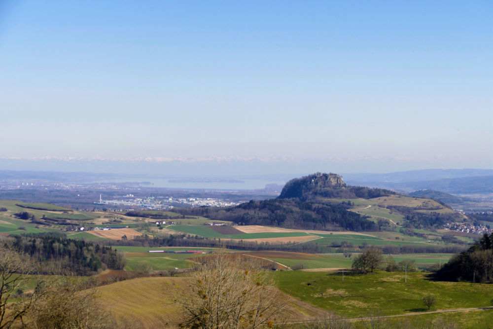 Blick auf den Hohentwiel mit Bodensee und im Dunst des Hintergrunds die Alpenkette.